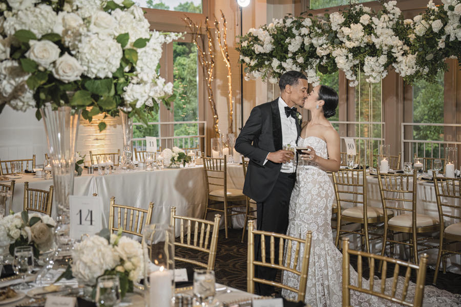 Couple kissing under a chandelier made of flowers in the Proximity Weaver Room